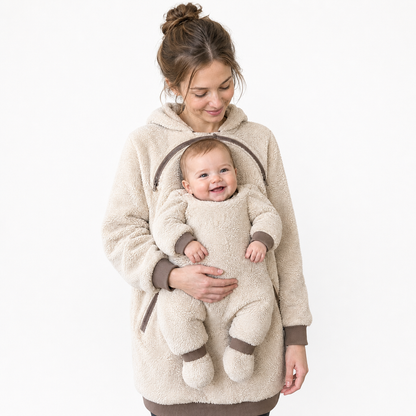 Mama mit Baby im cremefarbenen Kuschelmini-Hoodie vor weißem Hintergrund.